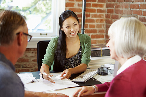 Young credit counsellor woman talking to a mature couple during a meeting in the office