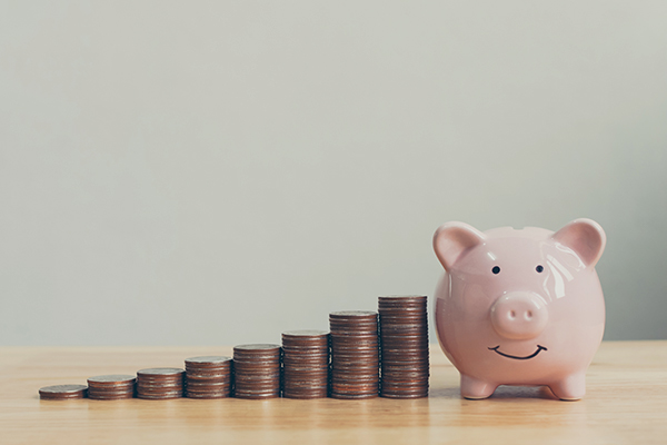 Stacks of coins sitting on the table with a piggy bank 