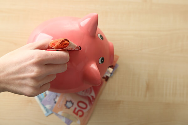 Hand putting banknote into pig money-box