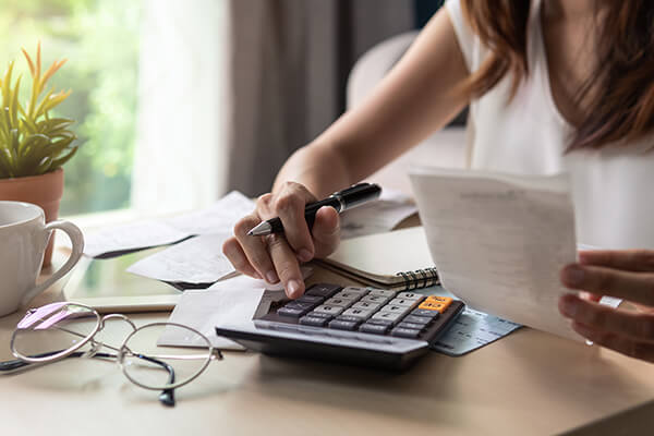 A woman calculates her credit card debts, loan debt and mortage payments using a calculator. 