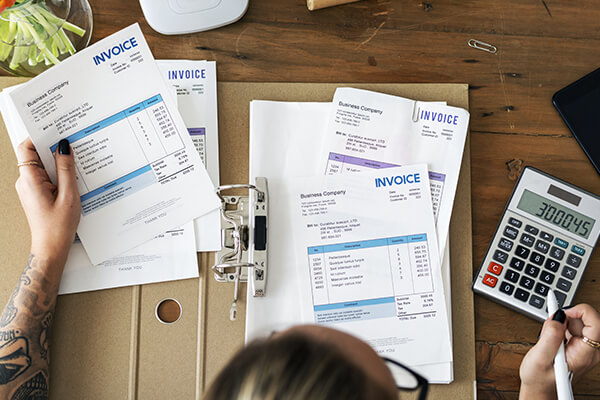 Top view of a person sitting on a table looking at invoices with a calculator 