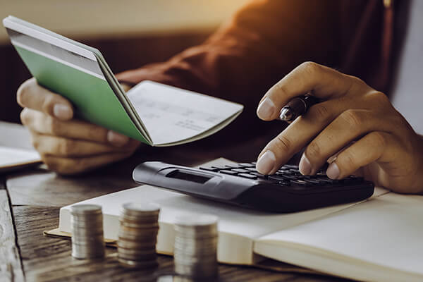 Man's hand using calculator checking his cheque book