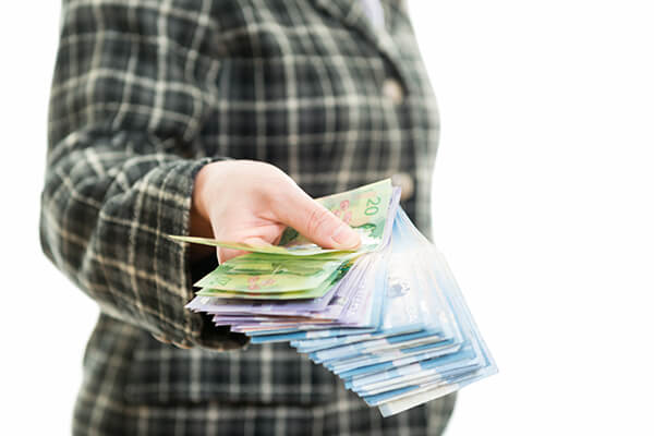 Woman holding bunch of Canadian dollar banknotes