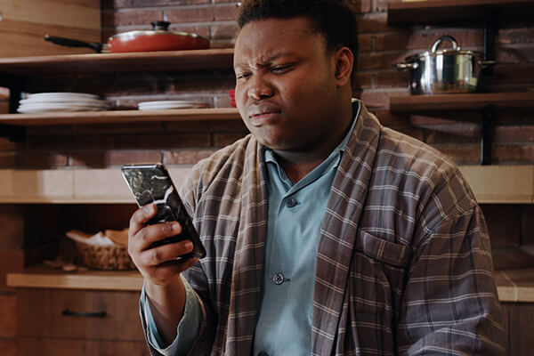 Upset man using his phone in a kitchen