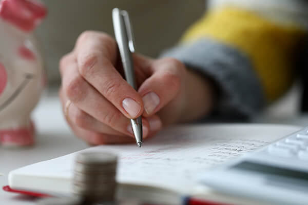 A person writing their budget in a notebook. 