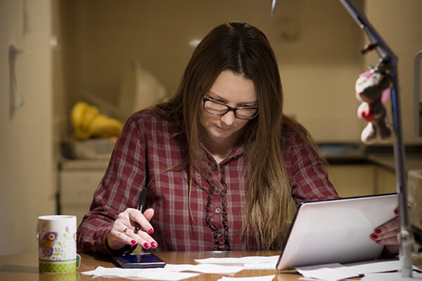 A woman uses her phone to browse information related to financial assitance from Communication and Utility companies. 