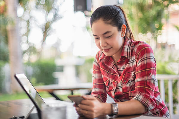 A woman checks her phone after researching debt settlement programs. 