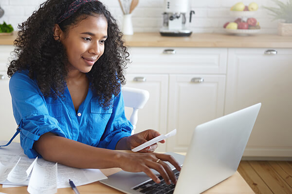 Woman tapping on a computer while holding a paper