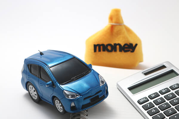 Blue plastic toy car next to a yellow bag with money written on it and a calculator