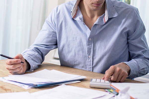 A man holding pen, taking notes and using a calculator