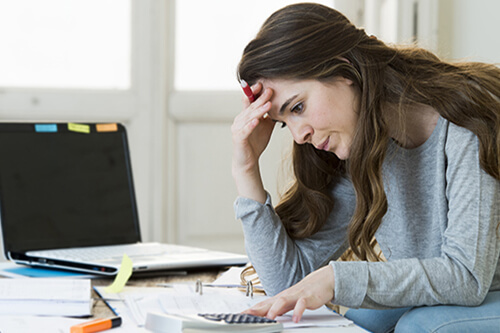 A woman stressed by a pile of debt she is dealing with.