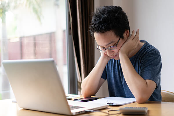 A man reviews his debt relief options while sitting in front of a of a laptop.