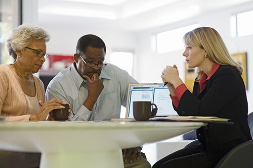 Mature couple looking anxious, sitting around the table and talking to a credit counsellor