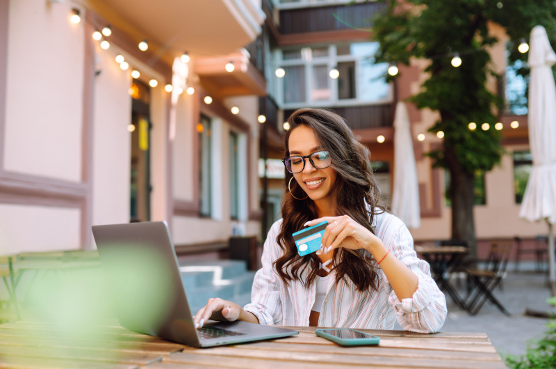 A woman use a credit card for online shopping on a laptop.