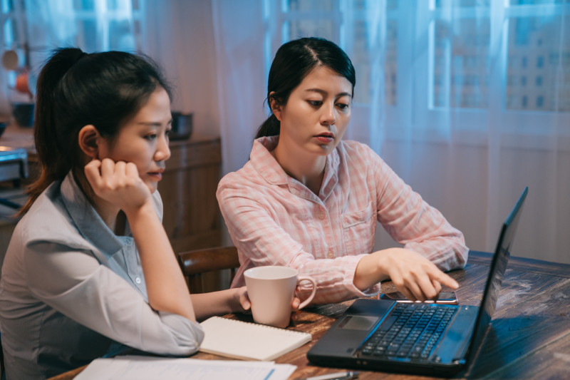 Two women are learning about budgeting and personal finances online on a laptop.