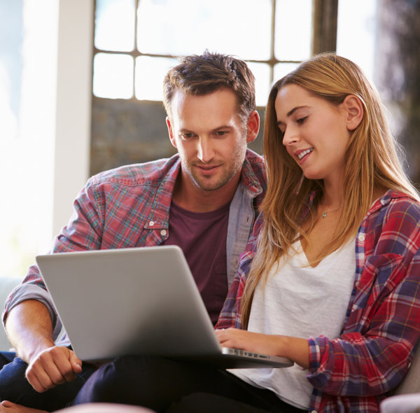 A couple sitting at home with a laptop computer attending an online workshop webinar.