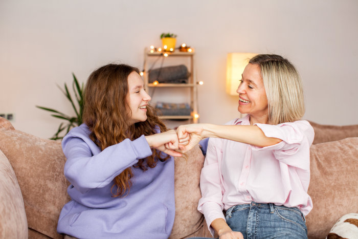 A mom talking with her teenage daughter at home about personal finances.