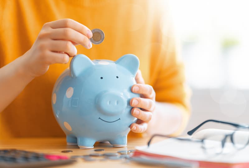 Person Putting Coin Into Piggybank