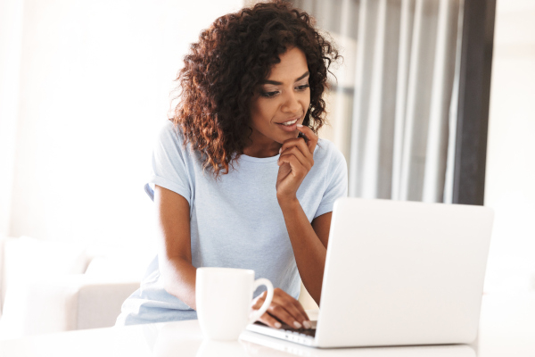 A woman looking at a laptop who is fully engaged, attending a financial online workshop.