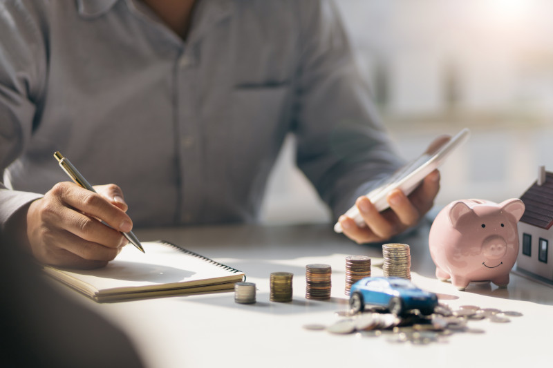 A guy with a notebook, pen, calculator, and money laid out on a table working to manage both his debt and his bills.