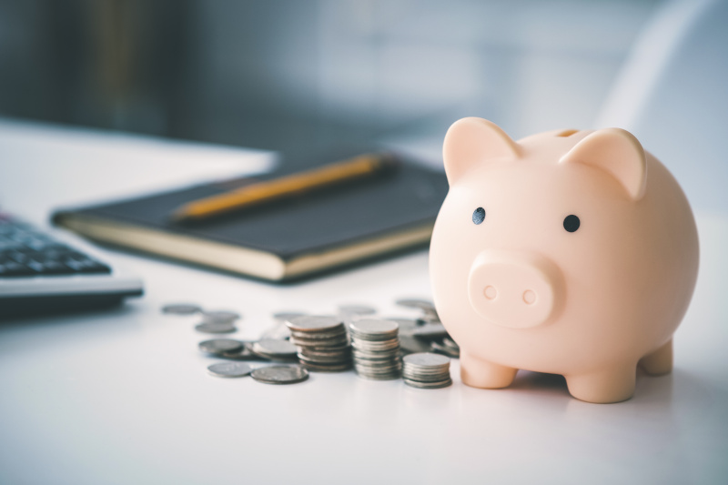 An image of a piggy bank, piles of coins, a calculator, a notebook, and pencil reflecting the process of budgeting and creating financial plans.