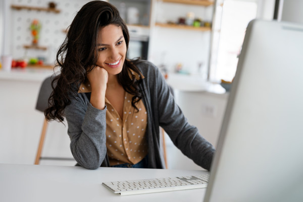 A woman attentively interacting with our website, nomoredebts.org, on her computer to learn how to manage her money better.