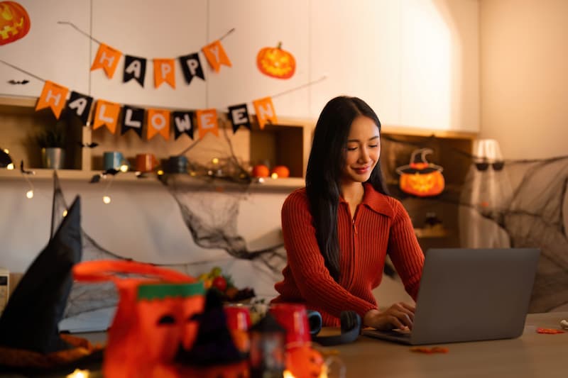 woman on laptop with Halloween decorations