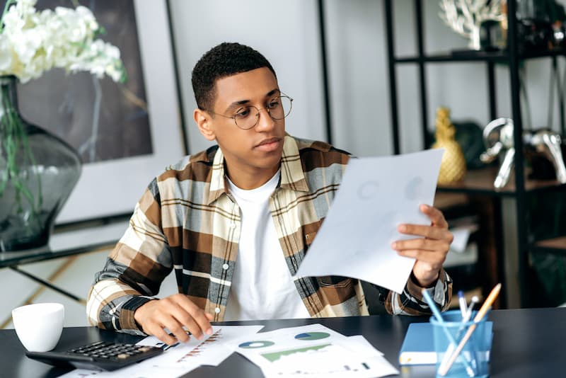 young adult looking at bills and at table