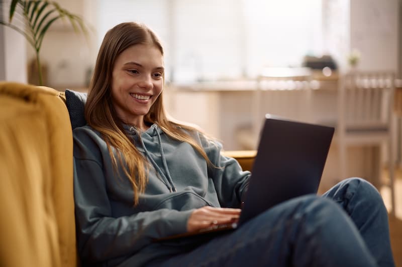 woman reading testimonials on laptop on couch