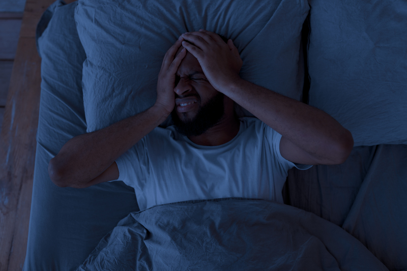 A sleepless man feeling sick because of his increasing debt load.