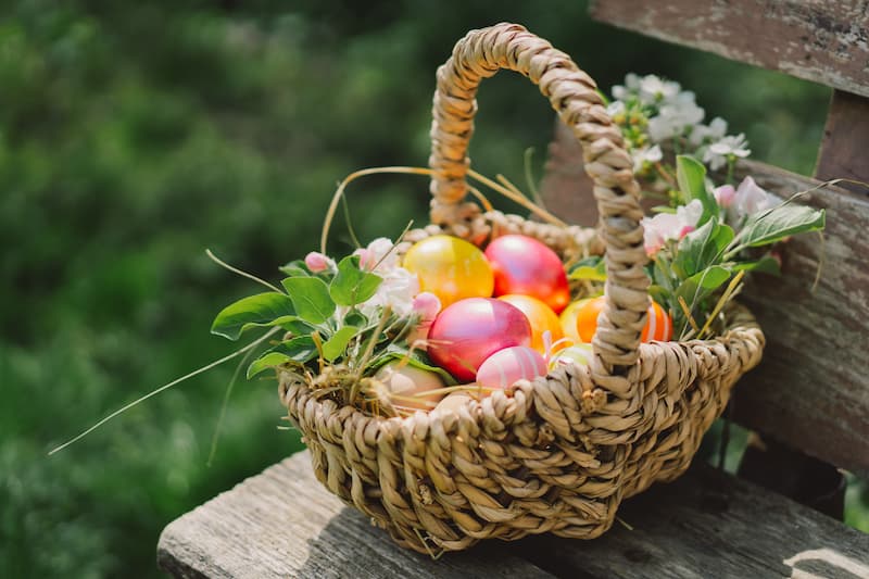 A beautiful Easter basket full of Easter eggs and flowers.